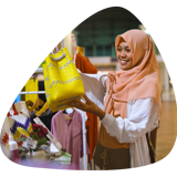 Customer in an Australian store smiles as she inspects a bright yellow woven bag